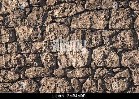 Nahaufnahme einer Wand aus gehauen Felsen, die mit Sonnenlicht beleuchtet werden Stockfoto