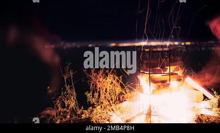 Ein kleines Lagerfeuer auf der linken Seite mit einem dunklen, verschwommenen Hintergrund Stockfoto