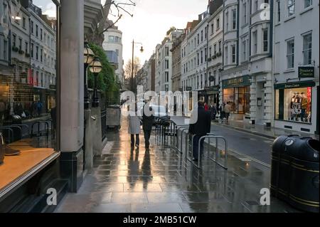 Leute, die auf dem nassen Bürgersteig in der Bond Street im Zentrum Londons spazieren Stockfoto