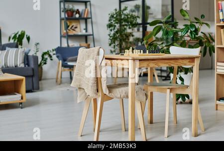 Horizontales Bild eines Tisches mit Schachbrett zum Spielen im Wohnzimmer Stockfoto