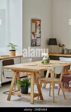 Vertikales Bild einer hellen, modernen Küche mit hölzernem Esstisch in der Mitte Stockfoto