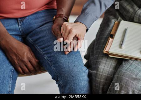 Nahaufnahme eines Psychotherapeuten, der Hand am Menschen hält und ihn während der Sprechstunde unterstützt Stockfoto