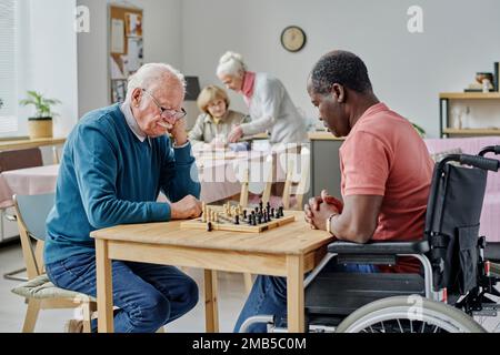 Ein älterer Mann, der mit seinem behinderten Freund Schach spielt, verbringt Zeit im Pflegeheim Stockfoto
