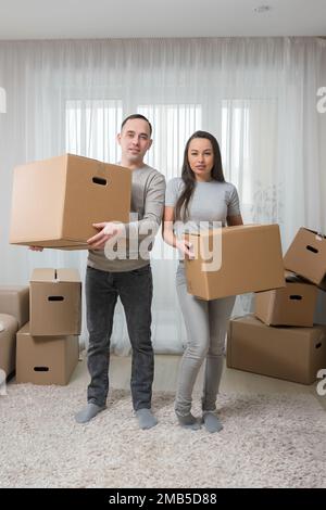Glückliches Paar, das am Umzugstag Spaß mit Pappkartons im neuen Haus hat Stockfoto