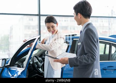 Junge Frau, die Autos kaufen will Stockfoto