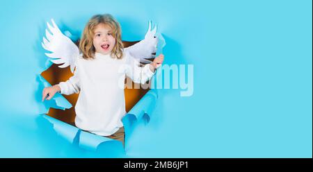 Kinderengel im Papierloch. Süßes Kind mit Engelsflügeln. Valentinstag-Konzept. Valentinstag-Banner. Stockfoto