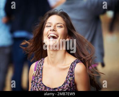 Festivalspaß. Eine schöne junge Frau, die lacht, während sie auf einem Outdoor-Festival ist. Stockfoto
