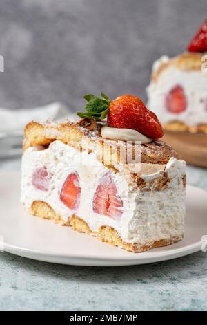 Erdbeerkuchen und Schlagsahne. Erdbeeren- und Cremetorte auf dem Teller. Schließen Stockfoto