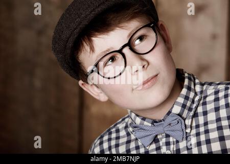 Intelligent und aufmerksam. Ein Junge in Retro-Kleidung, der eine Brille trägt, während er wegsieht. Stockfoto