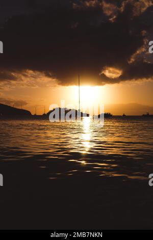 Eine vertikale Aufnahme eines dramatischen Sonnenuntergangs über dem Meer am Horizont Stockfoto