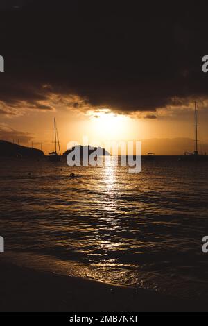 Eine vertikale Aufnahme eines dramatischen Sonnenuntergangs über dem Meer am Horizont Stockfoto