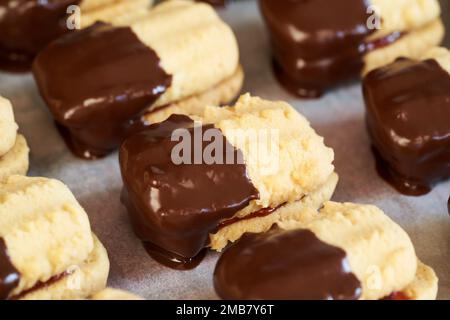 Abschluss hausgemachter traditioneller Weihnachtskekse gefüllt mit Erdbeermarmelade und in Schokolade getaucht Stockfoto