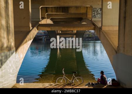 Radfahrer können einen Moment der Reflexion unter der Lamar Street Bridge über dem Ladybird Lake in Austin, TX, genießen. Stockfoto