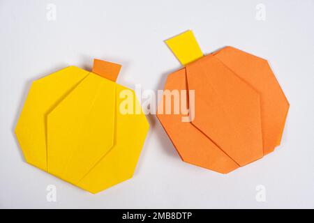 Halloween DIY Origami – Gelbe und orangefarbene Papierkürbis auf weißem Hintergrund Stockfoto