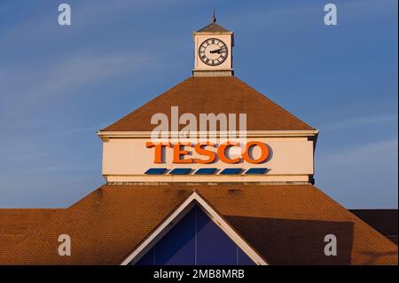 Eine Uhr auf dem lokalen TESCO Supermarkt bei Sonnenuntergang Stockfoto