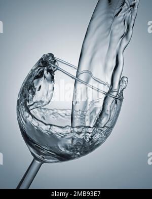 Ein Wasserstrahl, der in ein Glas strömt Stockfoto