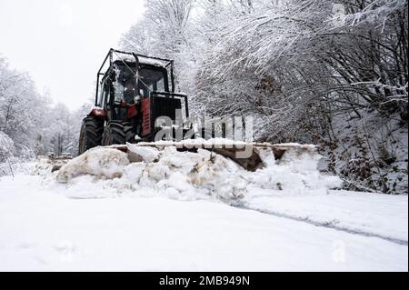 Ein Traktor, der Schnee von einer Bergstraße in den Karpaten in Polen schaufelt. Stockfoto