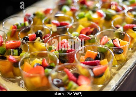 Großer Obstsalat in Glasschüsseln, bestehend aus geschnittenen Erdbeeren, Kiwi-Mangos und Trauben Stockfoto