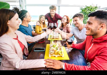 Fröhliche junge Leute, die Spaß miteinander haben, Wein im Penthouse auf einer privaten Heimparty trinken - trendige Freunde, die Zeit zusammen in der Restaurant-Lounge genießen - Stockfoto