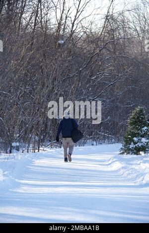 Ein Mann läuft durch eine schneebedeckte Gasse im Park Stockfoto