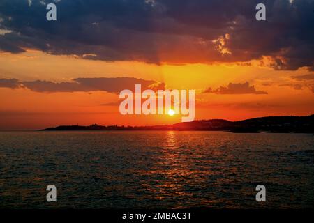Sonnenuntergang über dem Meer. Vanille-Orangenhimmel bei Sonnenuntergang mit Wolken und ruhigem Horizont. Eine horizontale Aufnahme des Himmels in lebendigen Farben Stockfoto