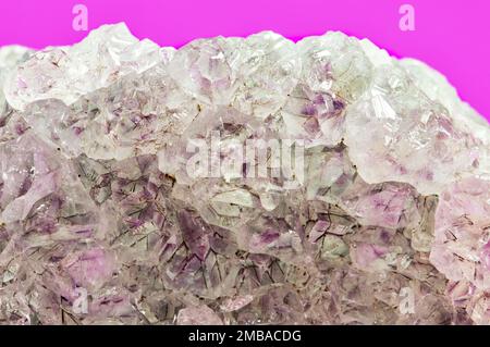 Helle, blass gefärbte Amethyst-Quarz-Kristalle in Rohmineralform auf purpurfarbenem Hintergrund. Stockfoto