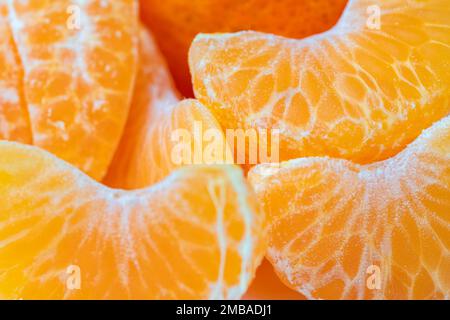Geschälte Mandarinenfruchtsegmente in einer Makro-, Hintergrund- und Texturphotographischen Zusammensetzung. Stockfoto
