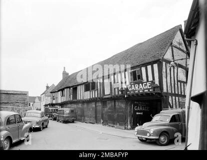 St Mary's Lane, Tewkesbury, Tewkesbury, Gloucestershire, 1961. Ein Blick aus dem Südosten mit einer Reihe mittelalterlicher, holzgerahmter Gebäude auf der Nordseite der St. Mary's Lane. Diese Gebäude mögen ursprünglich eine Reihe von Häusern gewesen sein, aber in den 1880er Jahren war zumindest das nahe Ende dieses Gebäudes Teil der St. Mary's Chemical Works, wo landwirtschaftliche Düngemittel importiert und hergestellt wurden. 1901 wurde es als landwirtschaftliches Ingenieurwerk für King's genutzt, der einen Laden in der High Street Nr. 9 hatte. Zwischen den späten 1920er und den 1960er Jahren wurde das Gebäude wie hier zu sehen als Garage genutzt Stockfoto