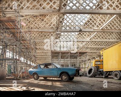 Old Sarum Airfield, Hanger 3, Laverstock, Wiltshire, 2020. Innenansicht des südöstlichen Hangars am Hangar 3, Old Sarum Airfield, mit „Belfast“-Dachbahnen über einem alten Auto im Vordergrund. Dieses Foto wurde aufgenommen, indem die Kamera durch eine Öffnung in einer Tür eingeführt wurde. Stockfoto