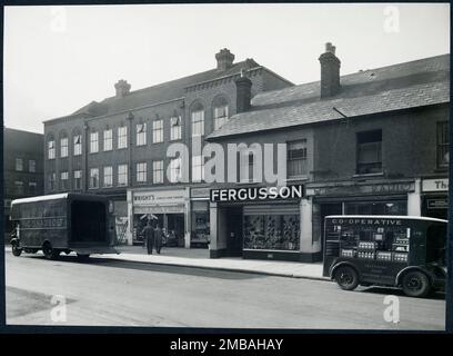 117-119 High Street, Waltham Cross, Broxbourne, Hertfordshire, 1948-1960. Blick vom Nordosten der 117-119 High Street, mit Schaufensterfronten, einem Umzugswagen und einem Milchwagen auf der Straße. Stockfoto