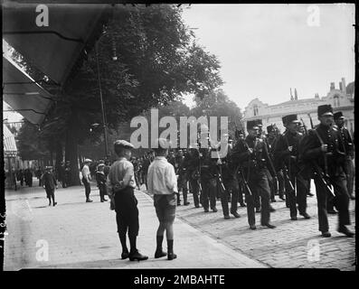 Den Haag, Niederlande, 1914. Nur 4 Tage nach Beginn des Ersten Weltkriegs mobilisieren sich Soldaten der niederländischen Armee in der Nähe des Vyver in Den Haag (Den Haag), wobei zwei Jungen im Vordergrund die vorbeimarschierenden Soldaten beobachten. Der Fotograf war bei Ausbruch des Ersten Weltkriegs in Holland im Urlaub und dieses Foto wurde nur 4 Tage später gemacht. Die Niederlande blieben neutral, aber um eine Invasion zu verhindern, mobilisierten sie am 1. August 1914 ihre Armee und transportierten Soldaten an die Landesgrenzen. Stockfoto