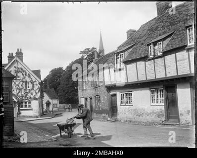 Church Street, Princes Risborough, Wycombe, Buckinghamshire, 1918. Ein Blick nach Westen entlang der Church Street in Princes Risborough, vorbei an einer Reihe von Holzhäusern aus dem 15. - Frühen 16. Jahrhundert und einem Mann mit einer Schubkarre, der die Straße reinigt. Die Häuser auf der rechten Seite des Vordergrunds wurden später im Jahr 1938 restauriert. Stockfoto