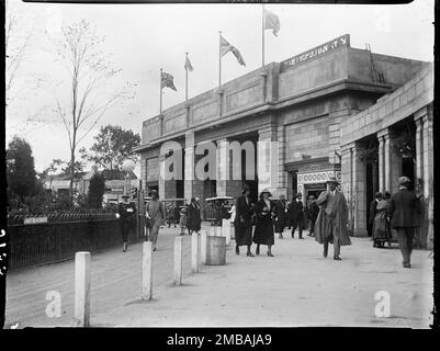 Wembley Park, Brent, Greater London Authority, 1924. Ein Blick in den Eingang der British Empire Exhibition im Wembley Park, der Menschen zeigt, die zum Ort gehen, und im Hintergrund die elektrischen Busse des Railodock. Die British Empire Exhibition wurde am St. George's Day 1924 eröffnet, um den Handel anzuregen und die Beziehungen zwischen den Ländern des Britischen Empire zu stärken. Bei den im Hintergrund dargestellten Eisenbahnbussen handelte es sich um Elektrobusse, mit denen Personen zwischen den verschiedenen Ausstellungsgebäuden auf dem Gelände befördert werden. Stockfoto