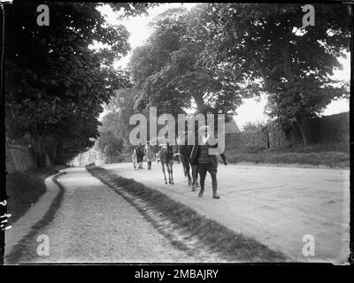 Fosse Way, Stow-on-the-Wold, Cotswold, Gloucestershire, 1928. Zwei Pferde und ihre Colts werden von zwei Männern auf der Stow Horse Fair entlang der Hauptstraße geführt. Stockfoto