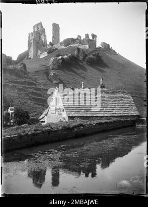 Ebermühle, East Street, Corfe Castle, Purbeck, Dorset, 1927. Blick nach Nordwesten über einen Mühlenteich in Richtung der Bäckerei, die heute als Ebermühle bekannt ist, und Corfe Castle auf dem Hügel dahinter, was sich auf dem Wasser im Vordergrund widerspiegelt. Zu der Zeit, als das Foto gemacht wurde, war die Ebermühle eine Bäckerei und ein Schild auf dem Gebäude draußen warb für Hovis-Brot. Stockfoto