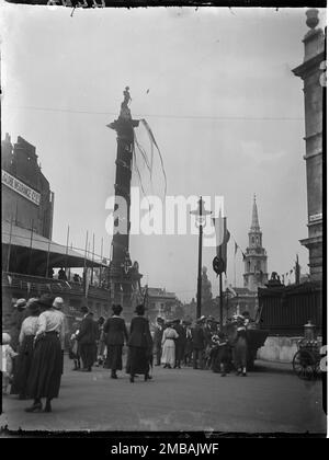 Trafalgar Square, St. James, Westminster, City of Westminster, Greater London Authority, 1919. Blick auf die Nelson-Säule und den Kirchturm von St. Martin in the Fields, der die Menschen auf dem Weg zum Trafalgar Square und seinen Friedensdekorationen zeigt. Dieses Foto gehört zu einer Gruppe, die der Fotograf am 18., 21. &Amp; 23. Juli 1919 aufnahm und die Friedensdekorationen aufnahm, die zum Friedenstag am 19. Juli 1919 in London zur Feier des Endes des 1. Weltkriegs errichtet wurden. Stockfoto