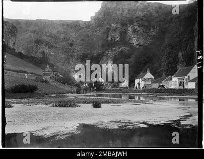 The Cliffs, Cheddar, Sedgemoor, Somerset, 1907. Ein Blick auf die Häuser an der Straße, bekannt als die Klippen, mit Cheddar Gorge dahinter, von Westen über den Teich in der Nähe von Cox's Mill und der Schleuse. Stockfoto