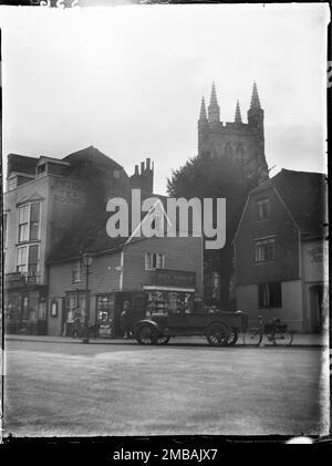 High Street, Tenterden, Ashford, Kent, 1926. Blick auf den Turm der St. Mildred's Church von Südosten auf der High Street, mit der Nummer 28 High Street und dem Woolpack Hotel im Vordergrund und einem Auto und Fahrrad auf der Straße. Stockfoto