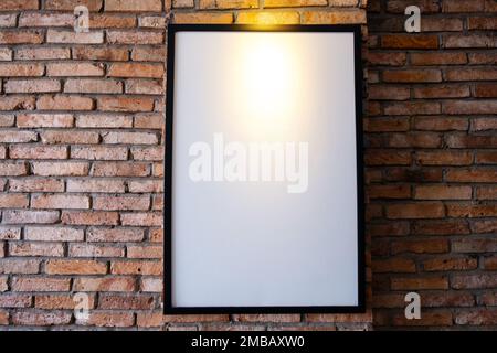 Modell-Poster an einer Backsteinwand. Vorlagenanzeige für Ihre Werbung oder Ihr Branding im Innenraum im Loftstil. Stockfoto