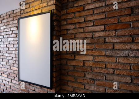 Modell-Poster an einer Backsteinwand. Vorlagenanzeige für Ihre Werbung oder Ihr Branding im Innenraum im Loftstil. Stockfoto