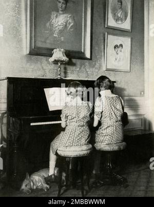 'Duet - 1940', 1947. Prinzessin Elizabeth (zukünftige Königin Elizabeth II) und ihre jüngere Schwester Prinzessin Margaret Rose spielen Klavier in passenden Kleidern. Ein Corgi liegt ihnen zu Füßen. Von "Prinzessin Elizabeth: The Illustrated Story of 21 years in the Life of the Thron Presumptive" von Dermot Morrah. [Odhams Press Limited, London, 1947] Stockfoto