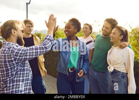 Eine Gruppe glücklicher junger Menschen gibt sich gegenseitig High Five während des Treffens auf der Straße der Stadt. Stockfoto