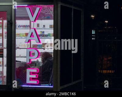 Vape Shop elektronische Zigarette Neonfarbene Fenster mit Anzeigeschildern leuchten auf, um Gäste nachts auf der Straße anzulocken. Concept Vape Shop. Stockfoto