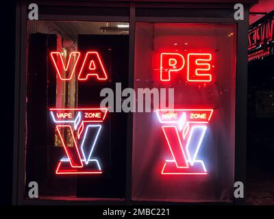 Vape Shop elektronische Zigarette Neonfarbene Fenster mit Anzeigeschildern leuchten auf, um Gäste nachts auf der Straße anzulocken. Concept Vape Shop. Stockfoto