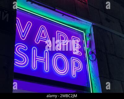 Vape Shop elektronische Zigarette Neonfarbene Fenster mit Anzeigeschildern leuchten auf, um Gäste nachts auf der Straße anzulocken. Concept Vape Shop. Stockfoto