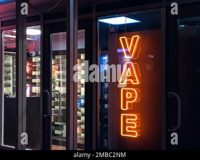 Vape Shop elektronische Zigarette Neonfarbene Fenster mit Anzeigeschildern leuchten auf, um Gäste nachts auf der Straße anzulocken. Concept Vape Shop. Stockfoto