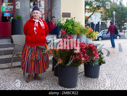 Funchal, Madeira - 27. Dezember 2019: Frau in Nationalkleidung ist Blumenverkäuferin auf dem Markt Mercado dos lavradores Madeira, Portugal Stockfoto