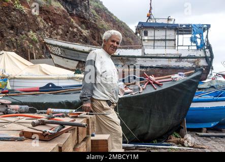 Madeira, Portugal, 23. Dezember 2019: Ein alter Fischer repariert sein Boot auf dem Meer Stockfoto