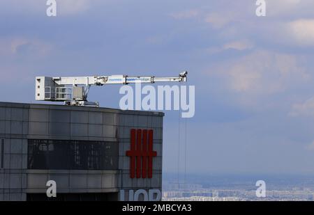 Kran auf einem Wolkenkratzer, der zur Erstellung des Systemservice für dient, reinigt die Glasfenster. Hochhäuser, moderne Gebäudeinstandhaltung. Stockfoto