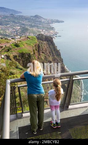 Madeira, Portugal, 25. Dezember 2019: Touristen am Cabo Girao Skywalk Aussichtspunkt. Funchal, die Hauptstadt von Madeira, Portugal, im Hintergrund. Stockfoto